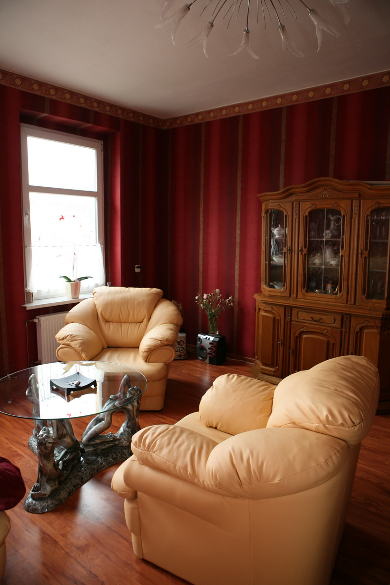 living room Modern living no nonsense Exotic-living-room-with-red-wallpaper-and-glass-top-table-cream-armchair-and-wood-floor-with-chandelier