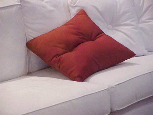 Красная подушка на белом диване